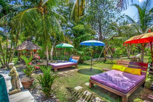 a garden with three chairs and umbrellas and a couch at Swasti Eco Cottages in Ubud