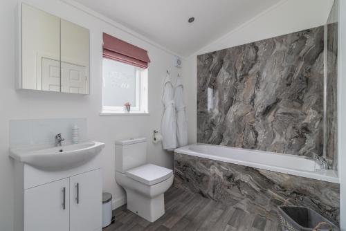een badkamer met een wastafel, een toilet en een bad bij Wolds Away in Huggate