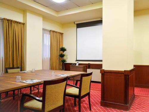 a conference room with a table and a projector screen at Mercure Reggio Emilia Centro Astoria in Reggio Emilia