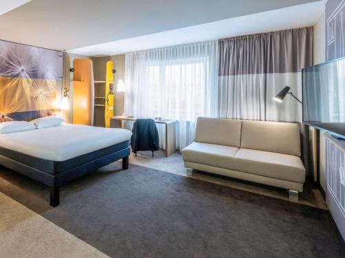 a hotel room with a bed and a couch at ibis Luebeck City in Lübeck