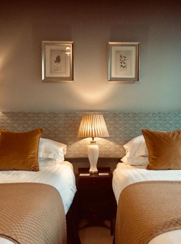 a hotel room with two beds and a lamp on a table at The Bridge House in Bridport