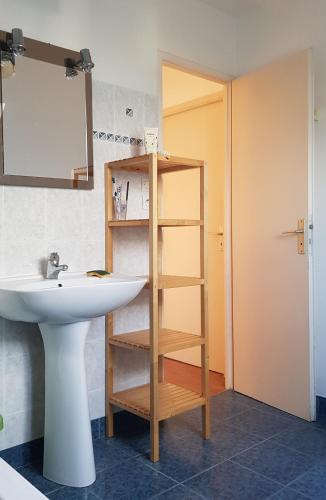 La salle de bains est pourvue d'un lavabo et d'une étagère à côté d'un miroir. dans l'établissement Maison de vacances bord de mer Sibiril Moguériec finistère la villa Léonie, à Sibiril