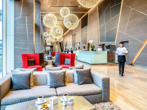 a man walking through a lobby with a couch at Novotel Bangkok IMPACT in Nonthaburi