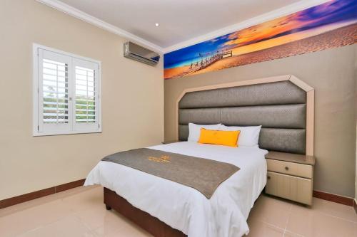 1 dormitorio con 1 cama y una pintura en la pared en African Sun lodge, en Durban