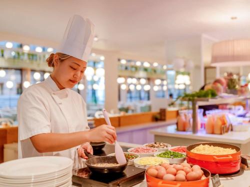 a woman preparing food in a kitchen at Mercure Brisbane King George Square in Brisbane