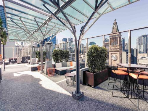 a rooftop patio with tables and chairs on a building at Mercure Brisbane King George Square in Brisbane