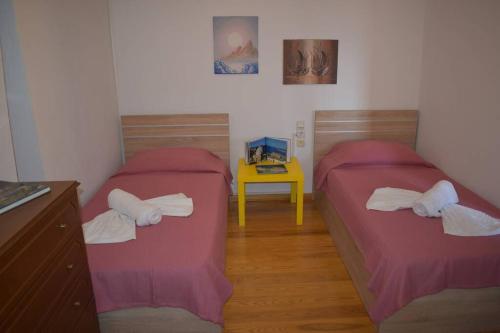 two beds in a room with a yellow table at Afissos View in Afissos