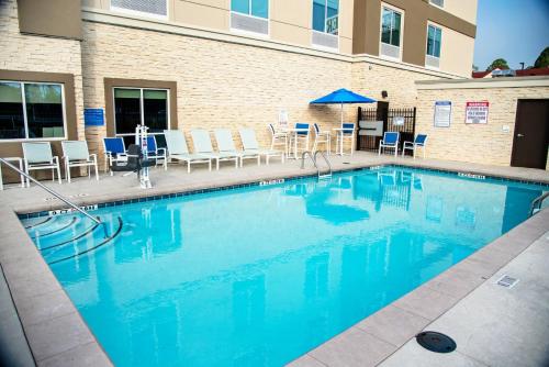 a large swimming pool with chairs and a table at Holiday Inn & Suites - Savannah Airport - Pooler, an IHG Hotel in Savannah