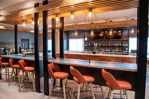 a bar in a restaurant with orange chairs at Holiday Inn & Suites - Savannah Airport - Pooler by IHG in Savannah
