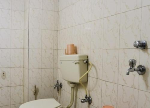 La salle de bains est pourvue de toilettes et d'un mur carrelé. dans l'établissement Hotel Maya Deluxe, à Hyderabad