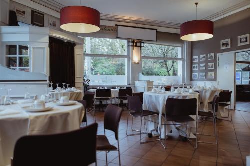 un comedor con mesas, sillas y ventanas en Hotel Le Centenaire Brussels Expo, en Bruselas