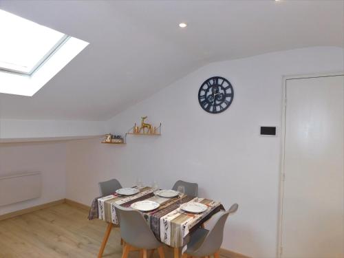 une table à manger avec des chaises et une horloge murale dans l'établissement Appartement climatisé 4 couchages à 600m du centre Thermal, à Lamalou-les-Bains
