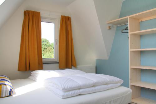 een slaapkamer met 2 witte bedden en een raam bij Sandy 36 in Callantsoog