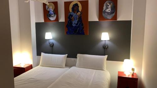 a bedroom with a white bed with two lamps at Migjorn in Oliva
