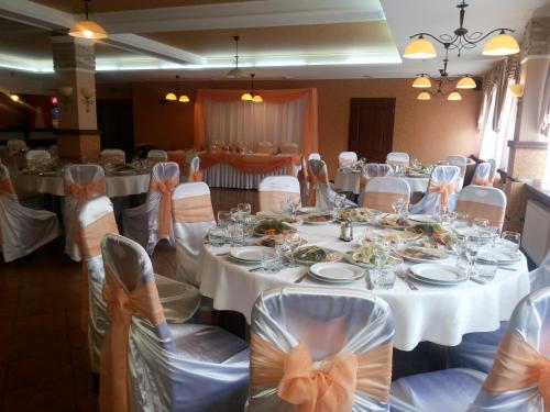 un salón de banquetes con mesas blancas y sillas con arcos en Shato Paradis Hotel en Irpin'