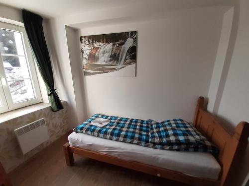 a bedroom with a bed with a plaid blanket on it at Apartmány pod Mariánskými schody in Albrechtice v Jizerských horách
