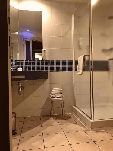 a bathroom with a shower and a stool and a mirror at Bes Hotel Bergamo Ovest in Mozzo