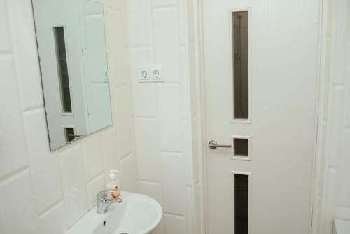 a white bathroom with a sink and a mirror at Apartments at Kontorska 10 in Kharkiv