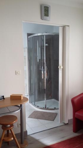 a glass shower in a room with a wooden table at La Chambre des Amis in Parthenay