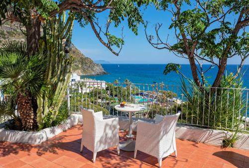 a patio with a table and chairs overlooking the ocean at Hotel San Giorgio Terme in Ischia