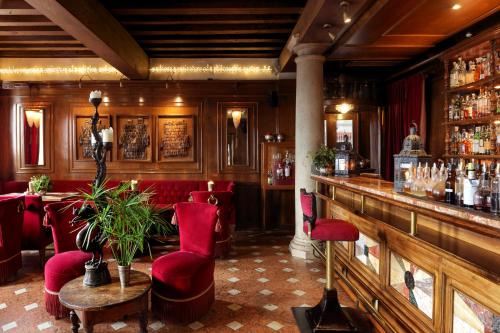 a restaurant with a bar with red chairs and a counter at Hotel Metropole Venezia in Venice