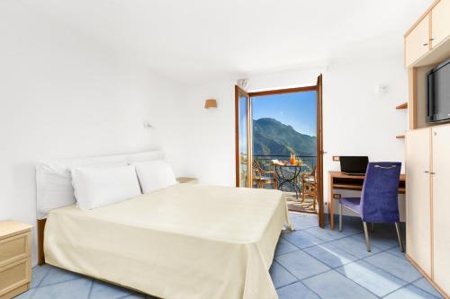 Schlafzimmer mit einem Bett, einem Schreibtisch und einem Balkon in der Unterkunft AMORE RENTALS - Residenza Rosalia 1 in Ravello