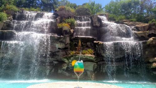 a waterfall in a pool with a drink in front of it at Hotel Fazenda Vista Alegre in São Lourenço