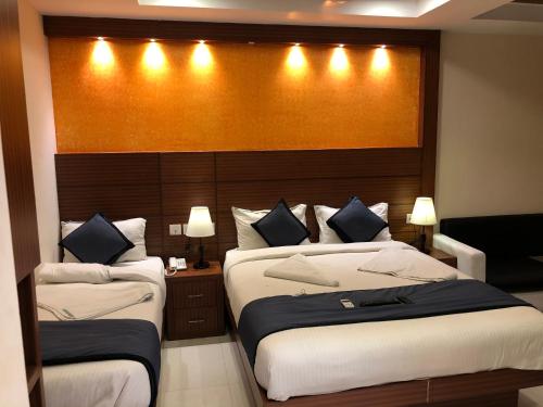 1 Schlafzimmer mit 2 Betten und einem Kopfteil mit Beleuchtung in der Unterkunft HOTEL SPARK RESIDENCY in Chennai