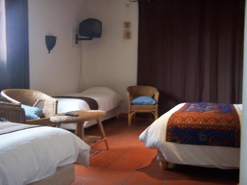 a hotel room with two beds and two chairs at Domaine de Granval Chambres d'Hôtes in Bretenoux