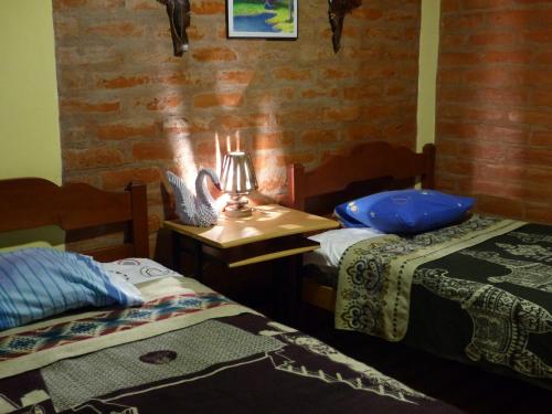 a room with two beds and a lamp on a table at Hostal La Casa Amarilla City in Baños