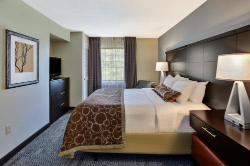a hotel room with a large bed and a television at Staybridge Suites Louisville - East, an IHG Hotel in Louisville