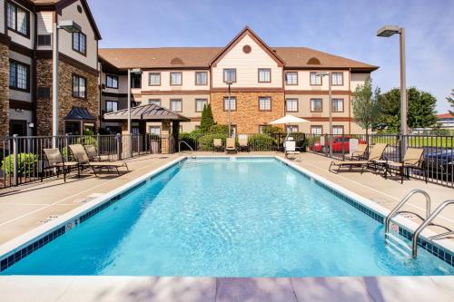 une piscine avec des chaises et un bâtiment dans l'établissement Staybridge Suites Louisville - East, an IHG Hotel, à Louisville