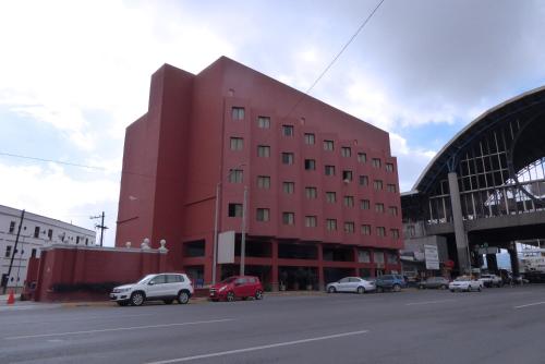 a red building with cars parked in front of a street at Hotel Son- Mar Monterrey Centro in Monterrey
