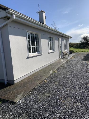 a white house with a bench in front of it at Hydrangea House in Kinsale