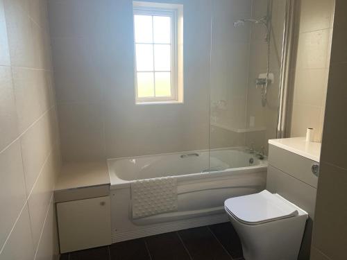 a bathroom with a tub and a toilet and a sink at Hydrangea House in Kinsale