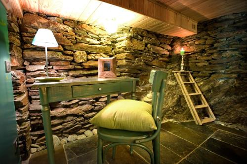 a stone room with a green desk and a chair at Le Mas du Coupétadou in Vialas