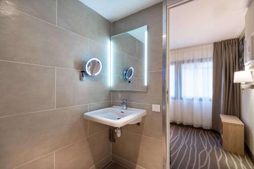 a bathroom with a sink and a mirror at Quality Hotel Toulouse Centre in Toulouse