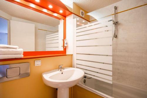 a bathroom with a sink and a mirror and a shower at Comfort Hotel Montlucon in Montluçon