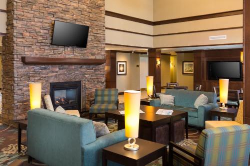 a hotel lobby with a fireplace and blue chairs at Staybridge Suites Toledo/Maumee by IHG in Maumee