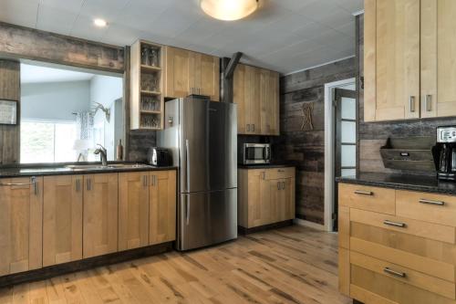 a kitchen with wooden cabinets and a stainless steel refrigerator at Escale du loup in Saint-Paulin
