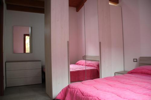 a bedroom with two beds with pink sheets and a mirror at Appartamenti Amaretto e Pardula in Fluminimaggiore
