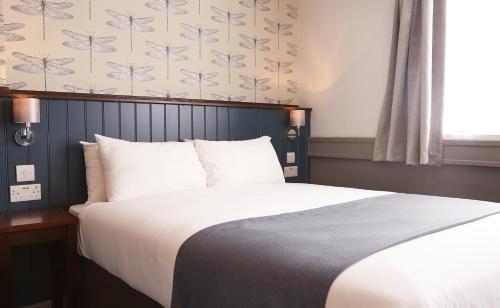 a bedroom with a large bed with white sheets at Corner House Inn by Greene King Inns in Newcastle upon Tyne