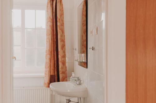 a white bathroom with a sink and a window at Pałac Wojciechy in Wojciechy