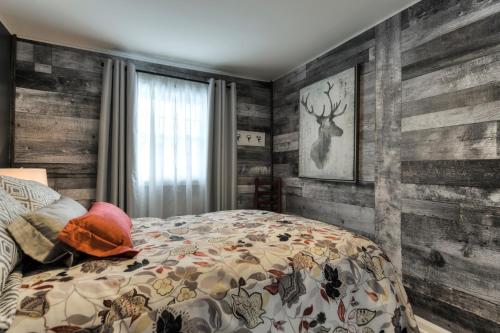 a bedroom with a bed and wooden walls at Escale du loup in Saint-Paulin