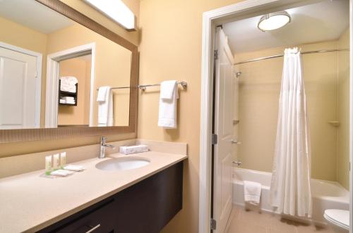 La salle de bains est pourvue d'un lavabo, d'un miroir et d'une douche. dans l'établissement Staybridge Suites Tomball, an IHG Hotel, à Tomball