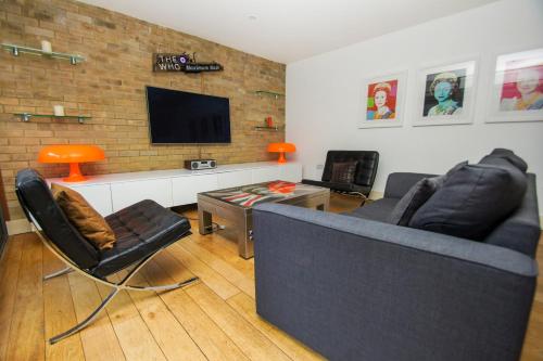 uma sala de estar com um sofá e cadeiras e uma televisão em The Edge - Parking - by Brighton Holiday Lets em Brighton & Hove
