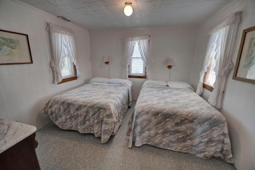 two beds in a small room with windows at Outer Banks Motel - Village Accommodations in Buxton