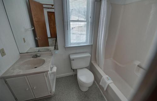 a bathroom with a toilet and a sink and a mirror at Outer Banks Motel - Village Accommodations in Buxton