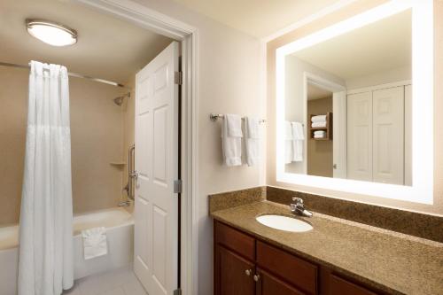 a bathroom with a sink and a mirror and a tub at Staybridge Suites Tampa East- Brandon by IHG in Tampa