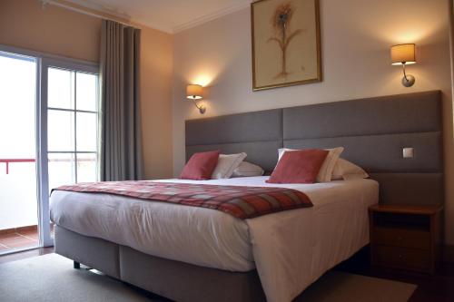 a bedroom with a large bed with red pillows at Hotel O Colmo in Santana